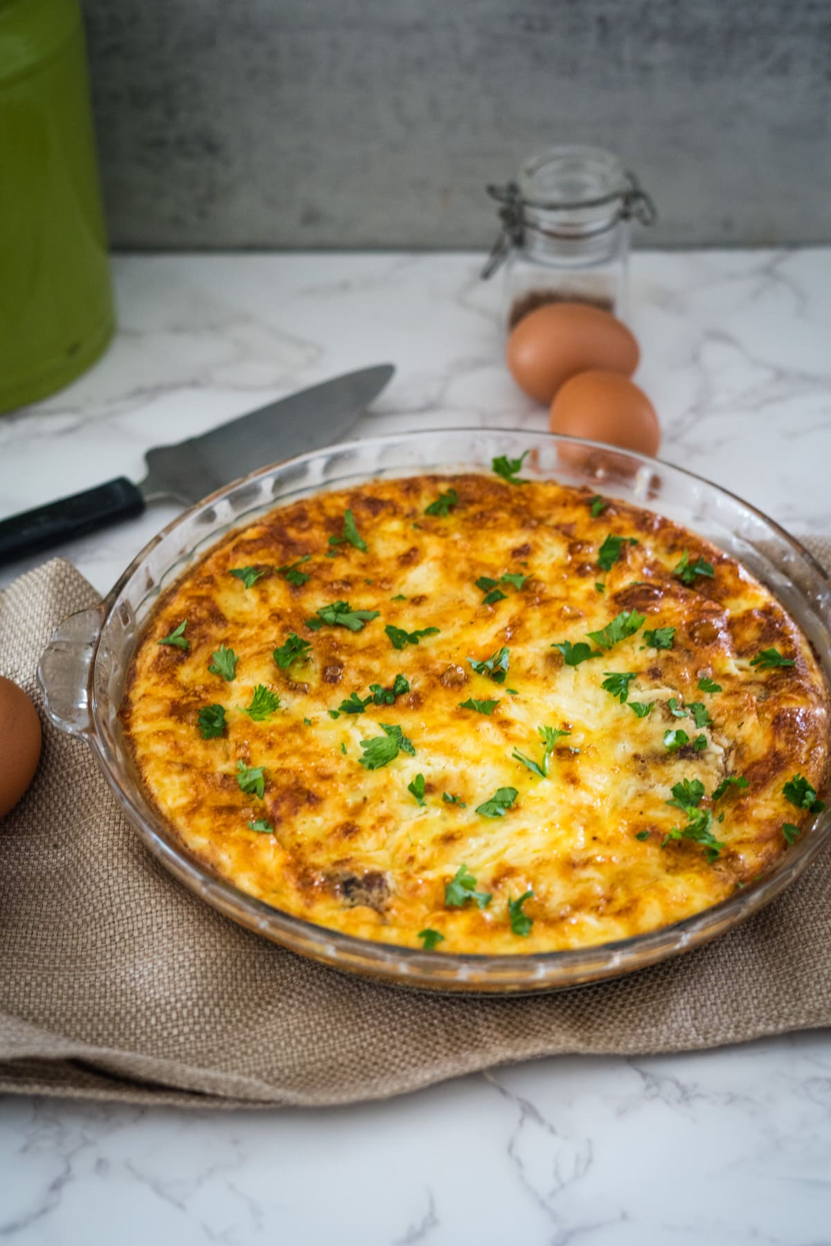 A quiche with eggs and parsley on a table.