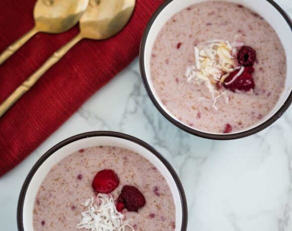 Two bowls of oatmeal with raspberries and coconut.
