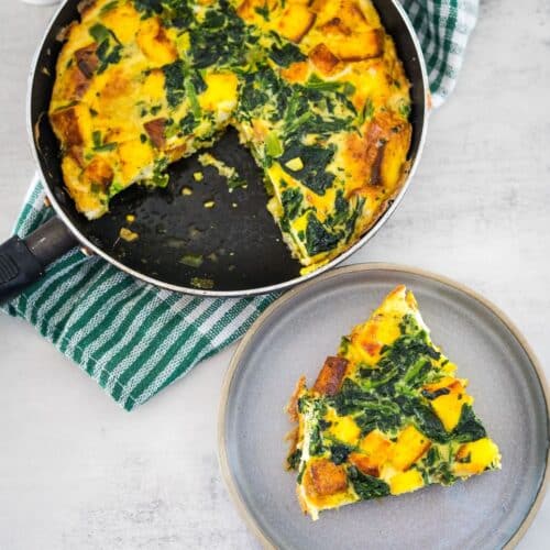 A slice of quiche with spinach on a plate.