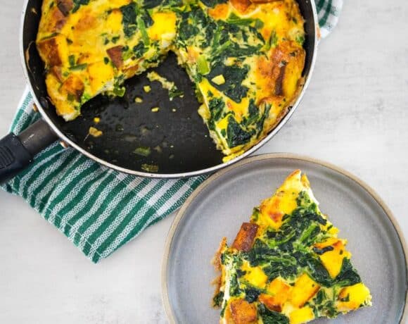 A slice of quiche with spinach on a plate.