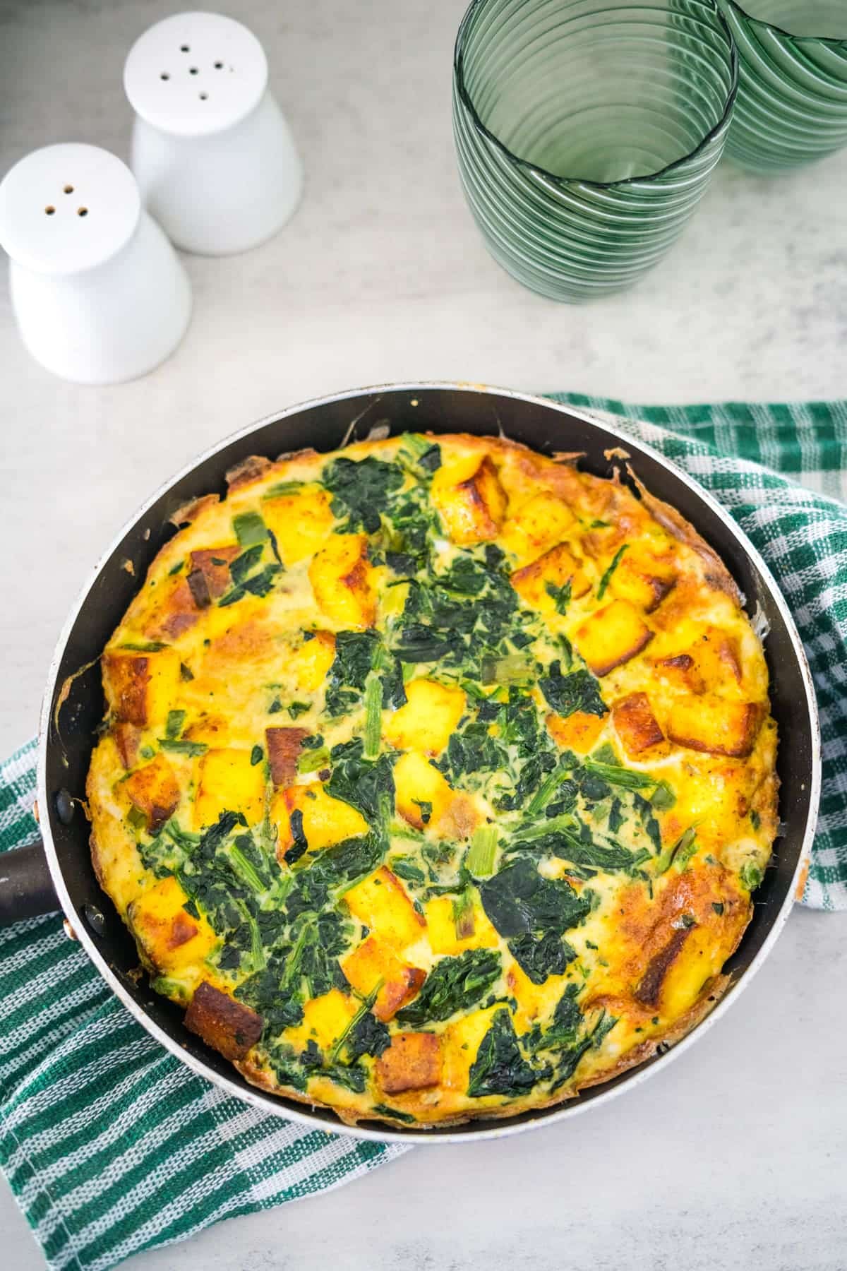 A quiche with spinach and cheese in a skillet.