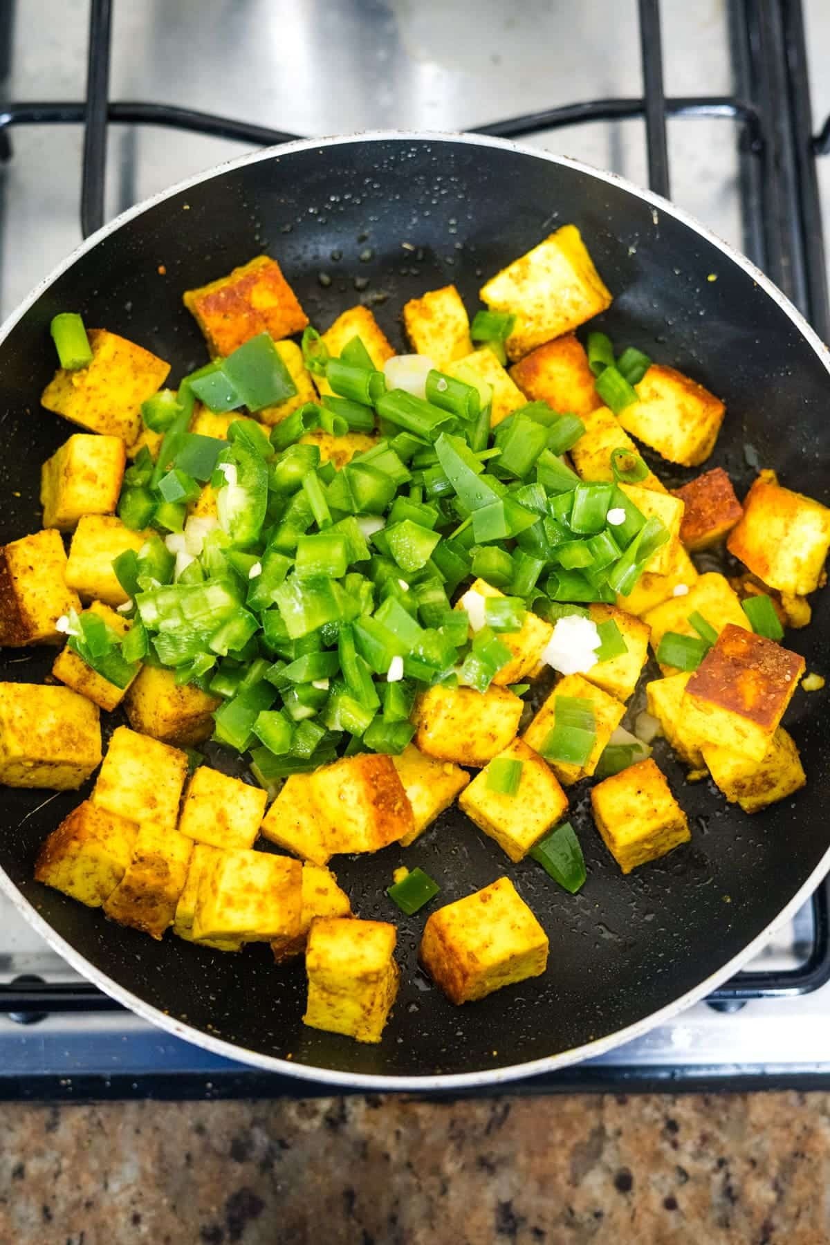 Tofu in a frying pan with green onions.